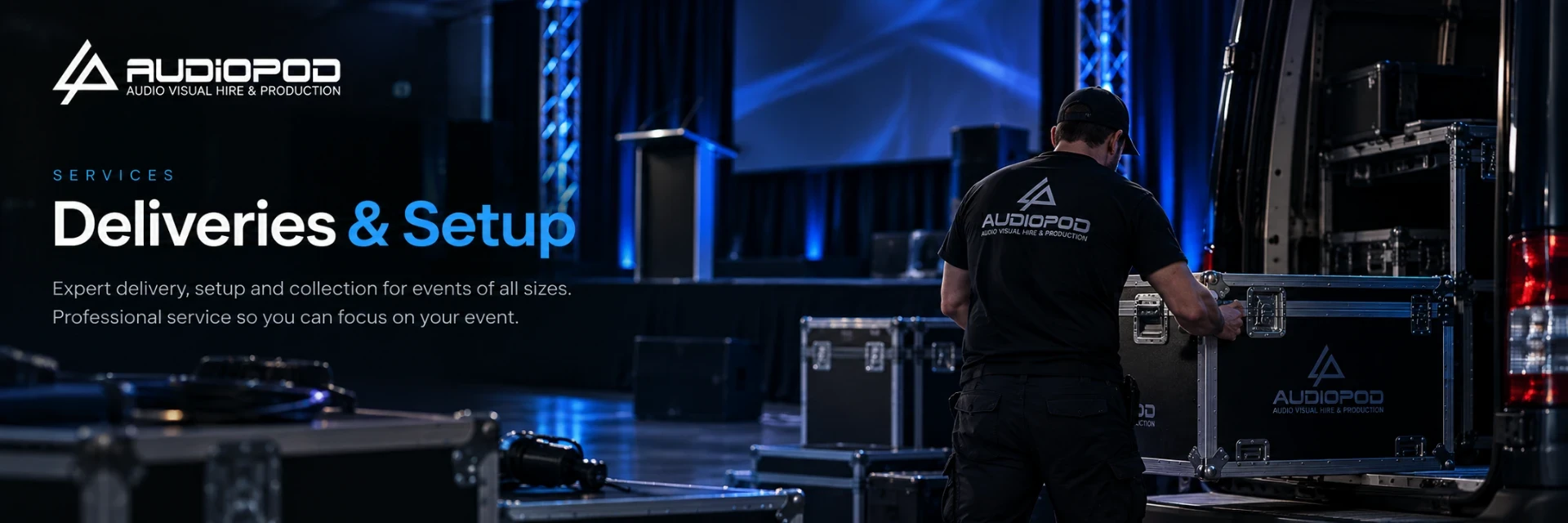 Audiopod technician unloading audiovisual equipment from a van at a blue-lit event venue.